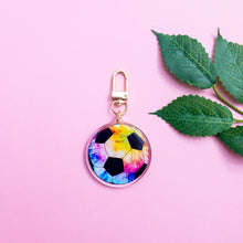 Load image into Gallery viewer, This is a Tie Dye Soccer Ball Keychain with a gold polished swivel clasp on a plain pink background
