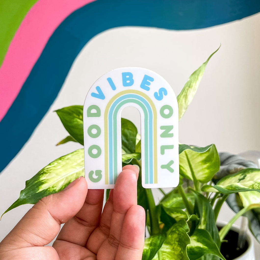 a person holding a Good vibes only sticker over an aesthetic background