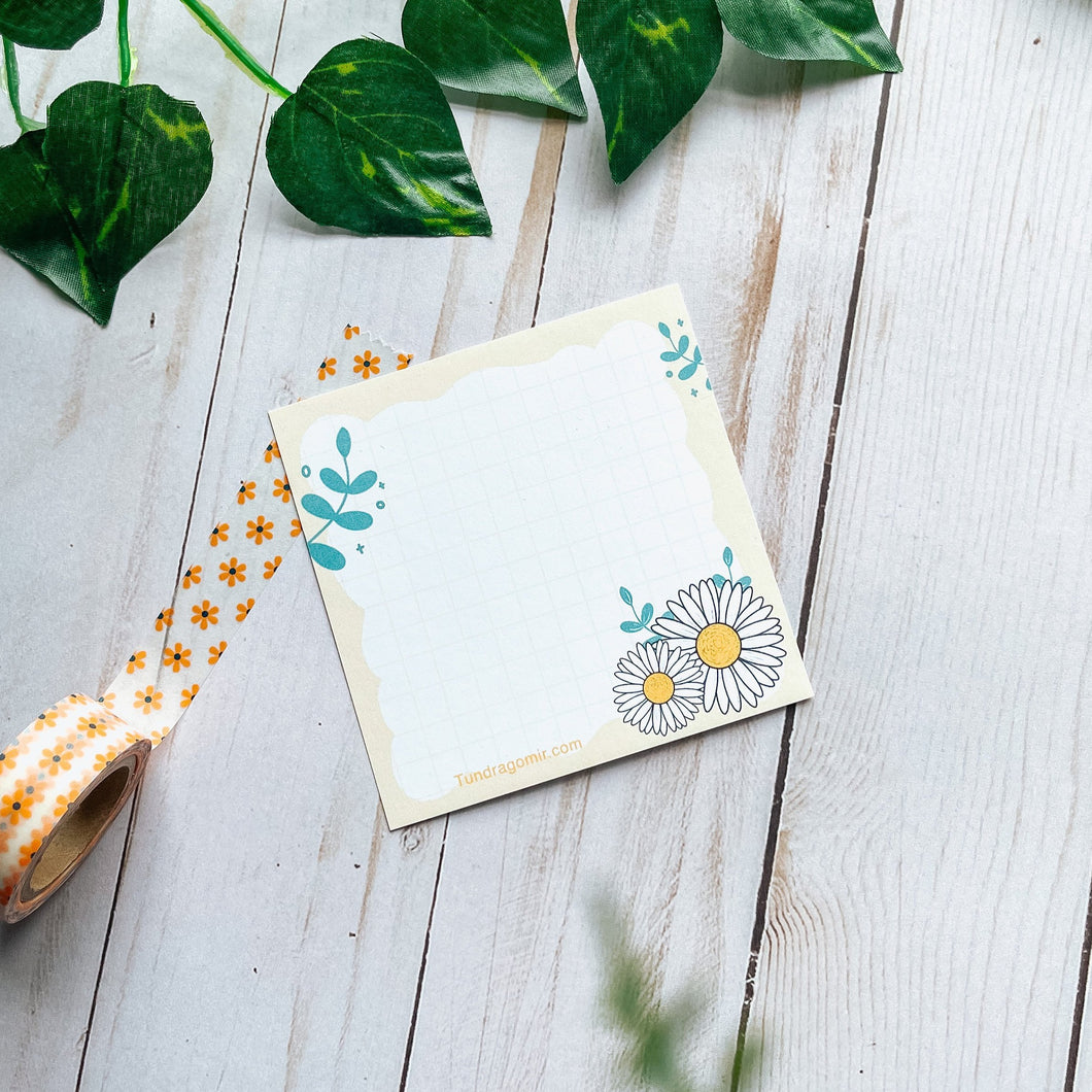 daisy flower  memopad/notepad  with green leaves an with the grid to help writee pretty notes. 
