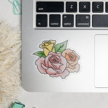 Load image into Gallery viewer, Clear floral sticker with the pink fully bloom flower in the front center, fully bloomed peach flower on the right side and the half bloomed yellow flower on the left accompanied by green leaves on the side. The sticker is on the side of the laptop next to the mouse pad. 
