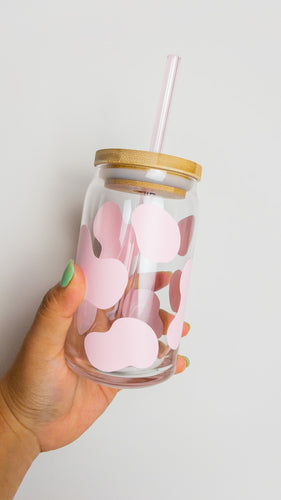 pink Cow Prin beer glass shaped can with a lid and a light pink straw being held against a white backdrop.